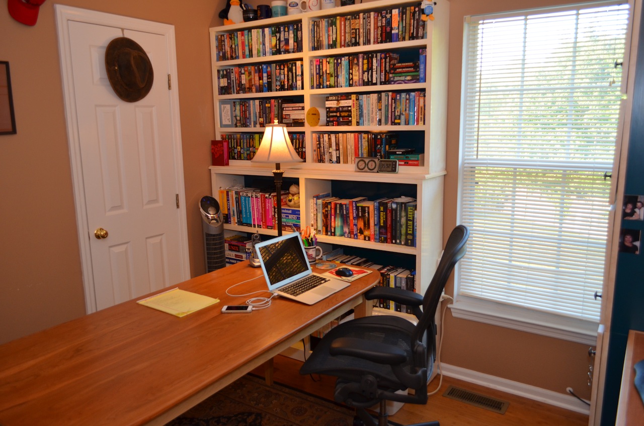 Brian's Office - cherry top table in foreground, laptop computer, shelves and books in background.