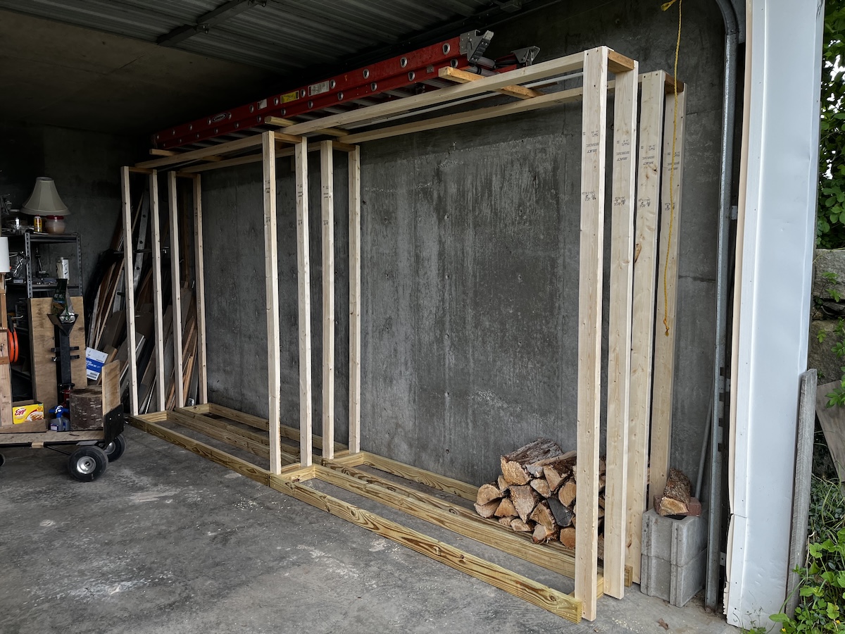 Firewood rack 16' long by 8' high built from 2x4 lumber in a concrete garage.