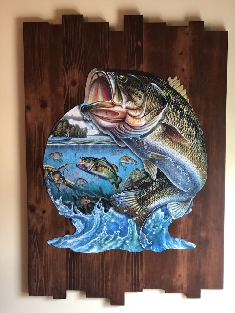 A fishy jigsaw puzzle mounted on wood, on the wall.